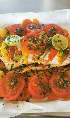 Un poisson garni de tomates et d'herbes sur une plaque à pâtisserie